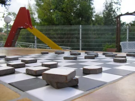 Detail of a large outdoor checkers board integrated into a stone table