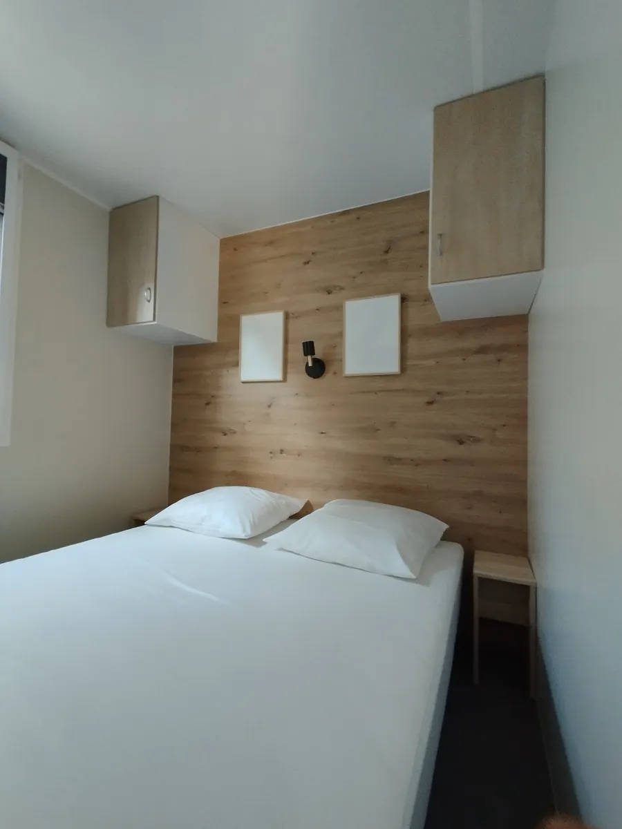 Bright double mobile home bedroom with overhead storage and wood-effect wall
