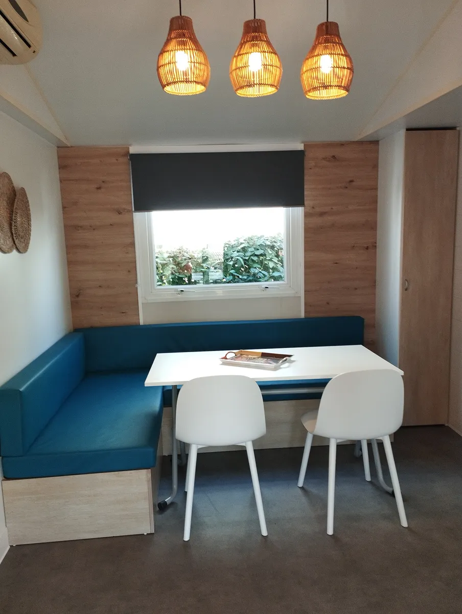 Modern mobile home dining area with blue corner bench, white table and designer chairs
