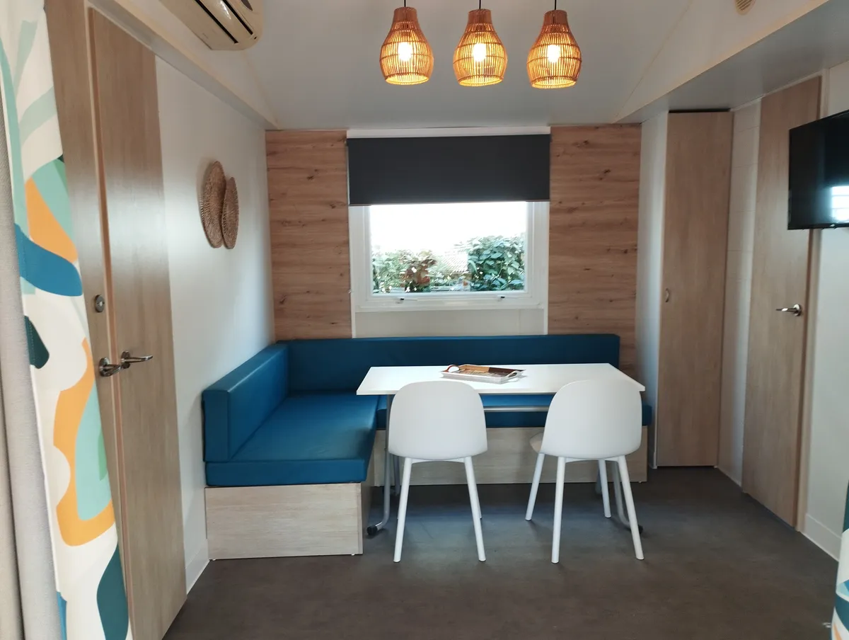 Mobile home living space with blue dining area, light wood doors and wall-mounted television