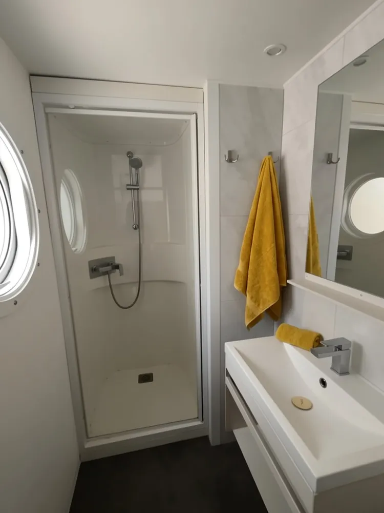 Sink area with round wooden-framed mirror and marble-effect wall in a mobile home