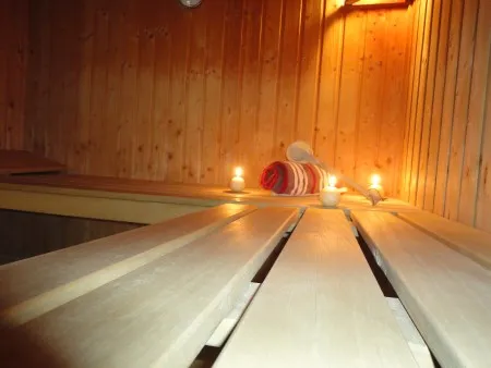 Intérieur en bois d'un sauna de camping avec banquettes, serviette roulée et bougies allumées