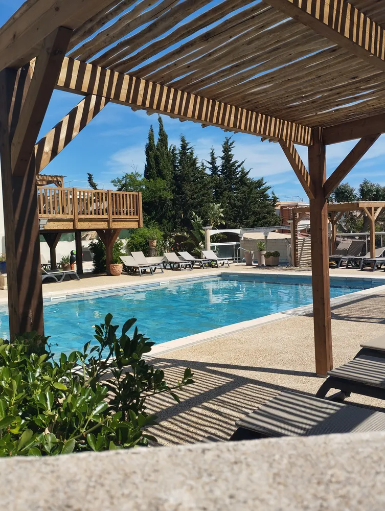 Lounger area shaded by a wooden pergola facing the pool